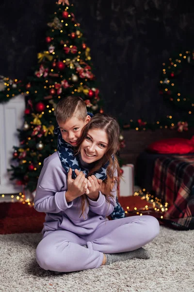 Mom and son at Christmas tree lights garland gifts new year — Stock Photo, Image