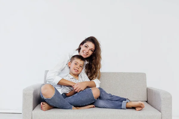 어머니와 어린 아들이 하얀 소파에 앉아 있는 모습 — 스톡 사진