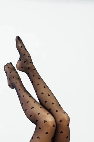Schöne schlanke Frauenbeine in schwarzen Strumpfhosen auf weißem Hintergrund — Stockfoto