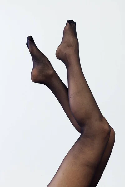 Belles jambes fines de femmes en collants noirs sur un fond blanc — Photo