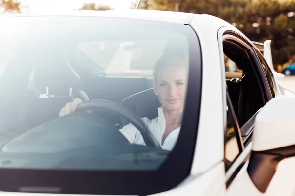 Hermosa conductora rubia al volante de un coche blanco — Foto de Stock