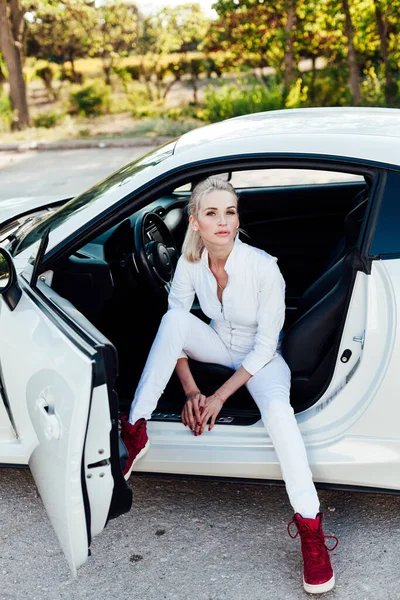 Hermosa conductora rubia al volante de un coche blanco — Foto de Stock