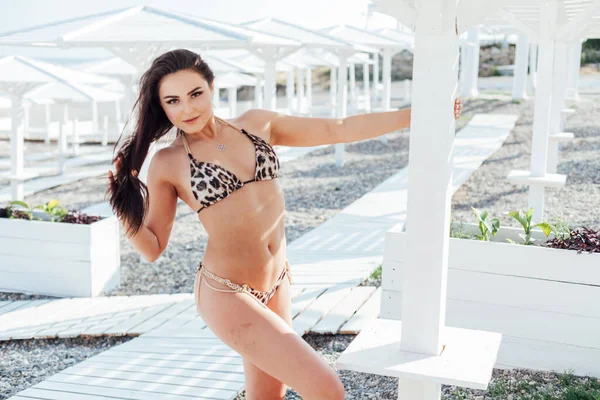 Modische brünette Frau im Badeanzug sonnt sich morgens am Strand am Meer — Stockfoto