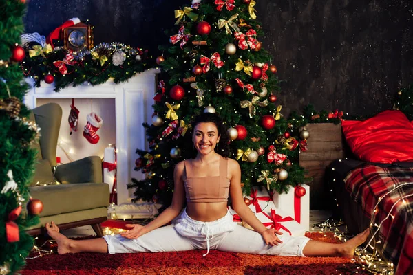 Piękna kobieta jogi asana gimnastyka na choince z prezentów noworocznych — Zdjęcie stockowe