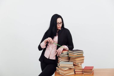 Sınıftaki güzel bayan öğretmen eğitim kitaplarıyla dolu bir masada.