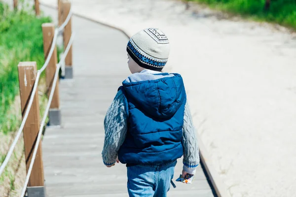 Kleiner Junge mit Hut und Jacke spaziert durch den Park — Stockfoto