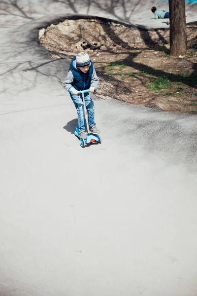 Menino monta uma scooter nas estradas do playground — Fotografia de Stock