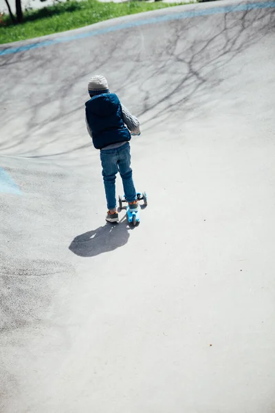 Menino monta uma scooter nas estradas do playground — Fotografia de Stock