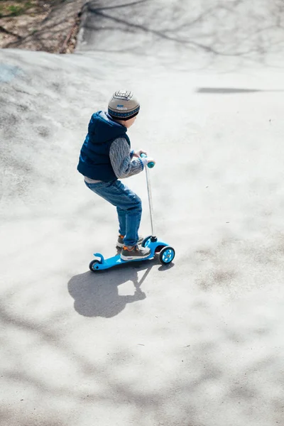 小さな男の子が遊び場の道路上のスクーターに乗る — ストック写真