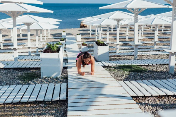 Piękna kobieta brunetka sport gimnastyka na plaży nad morzem — Zdjęcie stockowe