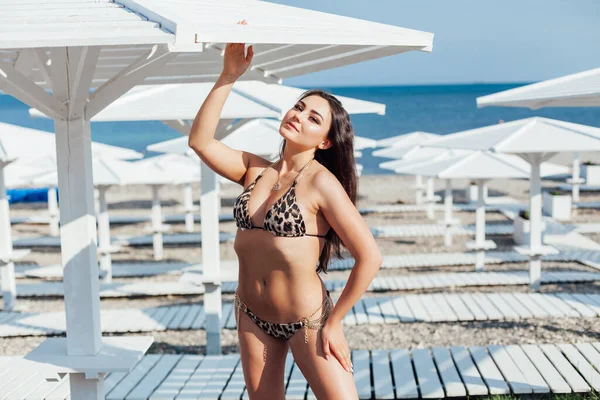 Красива жінка брюнетка в купальнику засмагає на пляжі біля моря — стокове фото