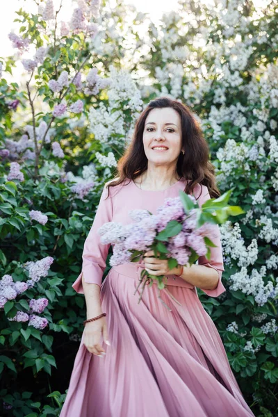 Retrato de uma mulher bonita em um vestido lilás com flores lilás — Fotografia de Stock