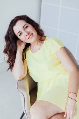 Sarı elbiseli güzel esmer bir kadının portresi.