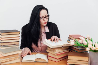 Eğitim kitaplarıyla dolu bir masada takım elbiseli güzel bir iş kadını.