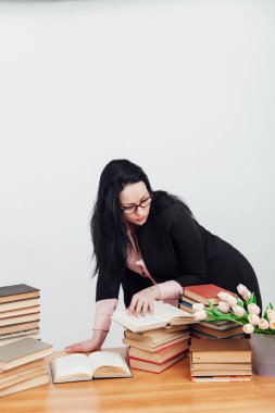 Eğitim kitaplarıyla dolu bir masada takım elbiseli güzel bir bayan öğretmen.