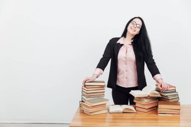 Eğitim kitaplarıyla dolu bir masada takım elbiseli güzel bir bayan öğretmen.