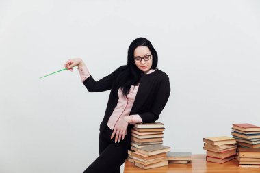 Sınıftaki güzel bayan öğretmen eğitim kitaplarıyla dolu bir masada.