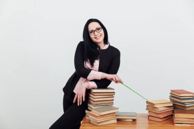 Sınıftaki güzel bayan öğretmen eğitim kitaplarıyla dolu bir masada.