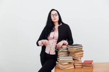 Sınıftaki güzel bayan öğretmen eğitim kitaplarıyla dolu bir masada.