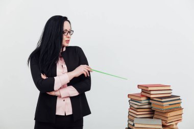 Sınıftaki güzel bayan öğretmen eğitim kitaplarıyla dolu bir masada.