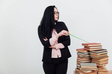 Sınıftaki güzel bayan öğretmen eğitim kitaplarıyla dolu bir masada.