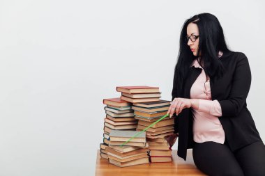 Sınıftaki güzel bayan öğretmen eğitim kitaplarıyla dolu bir masada.