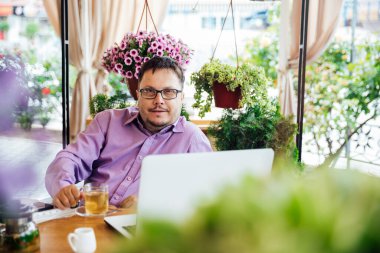 Lokantada tekerlekli sandalyede yemek yiyen engelli adam.