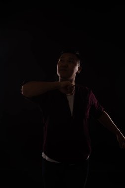 Asyalı bir adam karanlıkta müzik eşliğinde dans eder.
