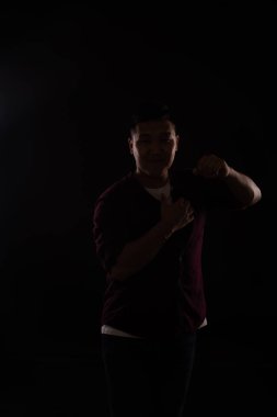 Asyalı bir adam karanlıkta müzik eşliğinde dans eder.