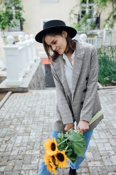 Hermosa mujer de moda en un sombrero negro con flores de girasol amarillo —  Fotos de Stock