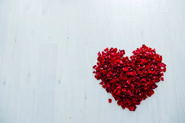 하얀 나무 배경 위에 선물하는 붉은 장미 꽃잎의 심장부 — 스톡 사진
