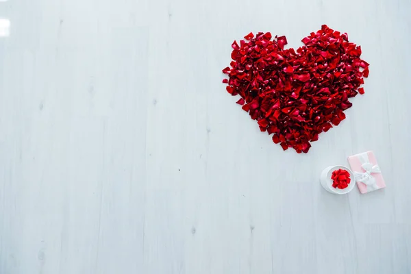 Corazón de rosa roja pétalos regalo sobre fondo de madera blanca — Foto de Stock