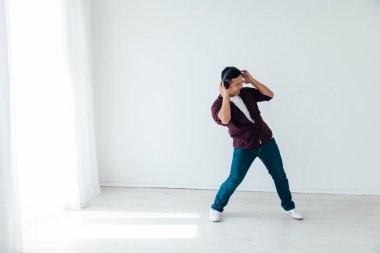 Güzel Asyalı adam kulaklıkla müzik eşliğinde dans ediyor.