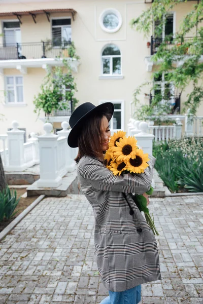 黄色のひまわりの花の黒い帽子の美しいファッショナブルな女性 — ストック写真