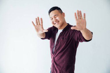 Güzel Asyalı adam beyaz odada müzik eşliğinde dans ediyor.