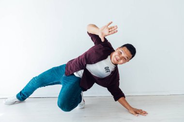 Güzel Asyalı adam beyaz odada müzik eşliğinde dans ediyor.