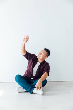 Güzel Asyalı bir adam beyaz bir odada yerde oturuyor.