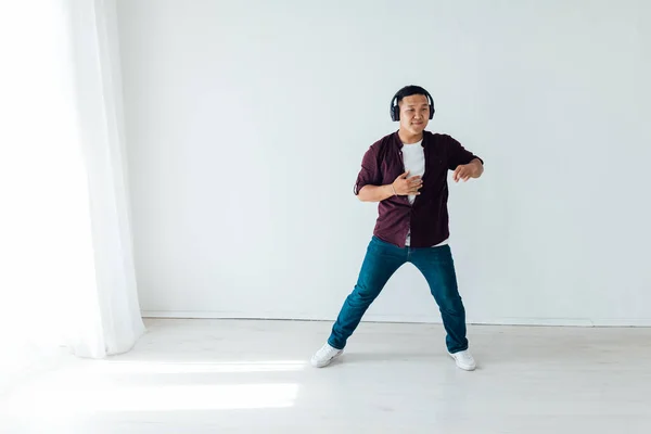 Hermoso asiático hombre baila a la música en los auriculares —  Fotos de Stock