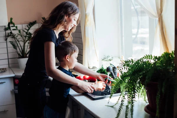 Mutter und Sohn waschen Gemüse mit Wasser in der Spüle — Stockfoto