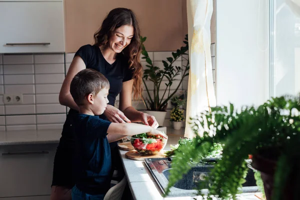 Anne ve oğul mutfakta sebze salatası hazırlayın.