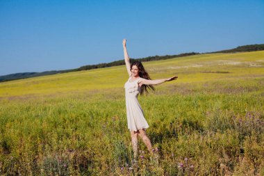 Doğada bir tarlada yürüyen elbiseli güzel bir kadın.