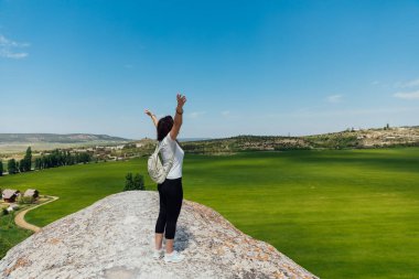 Güzel bir kadın uçurumun kenarında durmuş yolculuğun doğasına bakıyor.