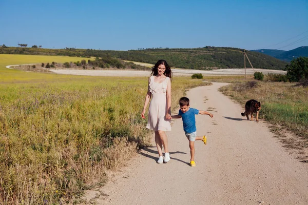 Mãe e filho caminham ao longo da estrada rural para o campo — Fotografia de Stock