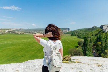 Esmer kadın uçurumun kenarında durmuş yolculuğun doğasına bakıyor.