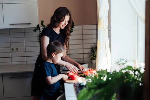 Mutter und Sohn bereiten in der Küche einen Gemüsesalat zu — Stockfoto