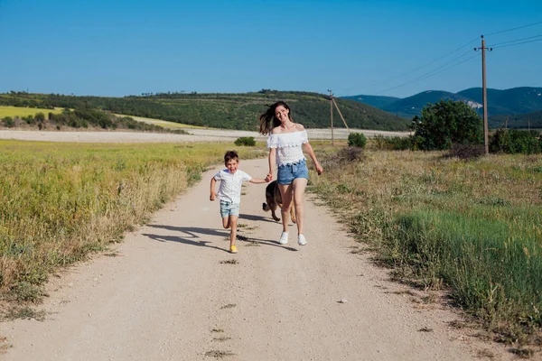 Mère et fils marchent le long de la route rurale vers le champ — Photo