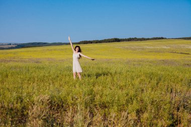 Doğada bir tarlada yürüyen elbiseli güzel bir kadın.