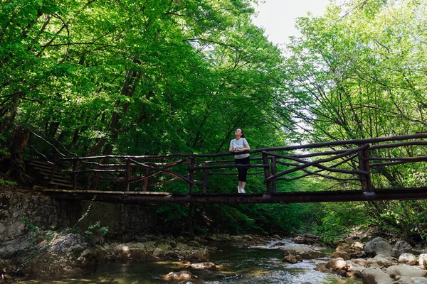 Güzel bir kadın yeşil orman doğa yolculuğunda bir dağ nehrinin kıyısında yürüyor. — Stok fotoğraf