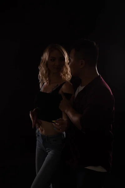 Un hombre y una mujer bailan juntos al son de la música en la oscuridad — Foto de Stock