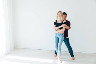 Güzel erkek ve kadın beyaz bir odada müzik eşliğinde dans ediyorlar.